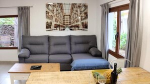 A modern living room with a grey sofa, a wooden coffee table, a wine bottle, and a bowl of fruit. - Apartment 'Finca Wapa - Finca' with Sea View, Wi-Fi and Air Conditioning (Frontera)