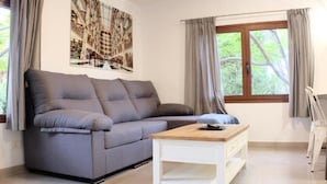 A modern living room with a grey sofa, a wooden coffee table, and a large window with curtains. - Apartment 'Finca Wapa - Finca' with Sea View, Wi-Fi and Air Conditioning (Frontera)