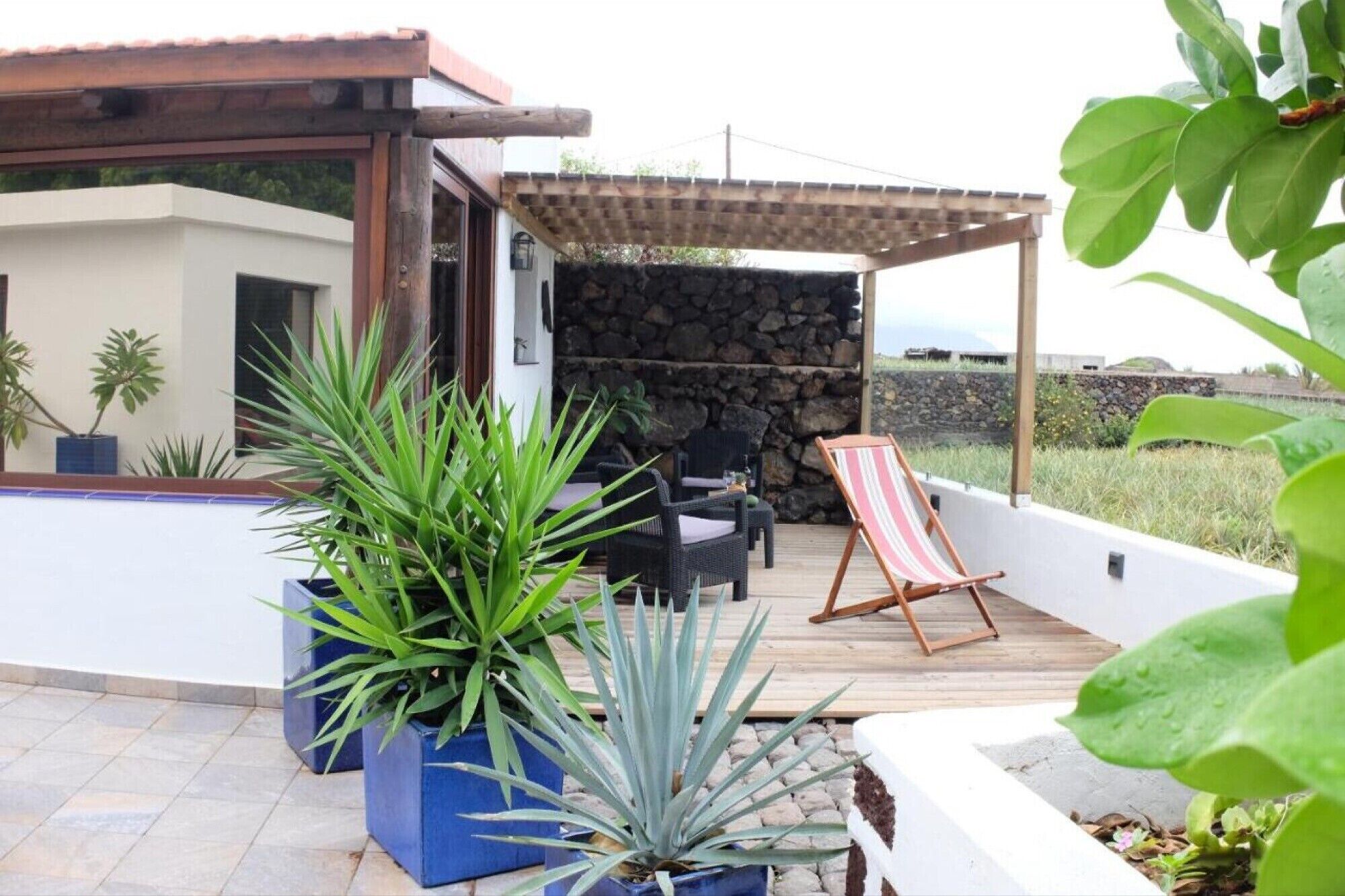 Un patio con plantas en macetas, mobiliario exterior y una pared de piedra.