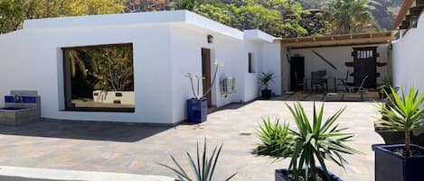A courtyard with a white building, potted plants, and a view of hills.