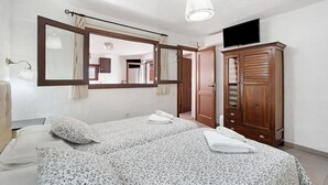 A bedroom with a bed, a wardrobe, a television, and a mirror.