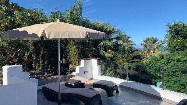 A rooftop terrace with lounge chairs, a large umbrella, and lush greenery in the background. - Apartment 'Finca Wapa - Apartamento Mayor' with Sea View, Wi-Fi and Air Conditioning (Frontera)