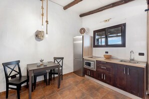 Une cuisine équipée d’une table à manger, de chaises, d’un réfrigérateur, d’un four à micro-ondes et de meubles de rangement en bois.