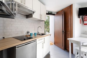 Una cocina con lavavajillas de acero inoxidable, un lavamanos y encimera de madera.