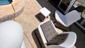 Ein Poolbereich mit Pool, einem Stuhl, einem kleinen Tisch und einer Glastür zu einer überdachten Terrasse.