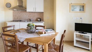 Eine Küche mit weißen Schränken, einem Herd und einem Fernseher auf einem Schrank.