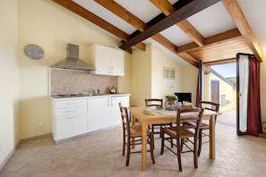 Une cuisine avec des armoires blanches, un plafond en bois et une table à manger avec des chaises.