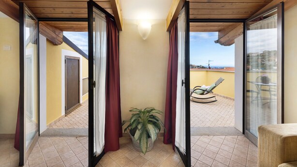Ein Balkon mit einem Blumentopf, einem Stuhl und Blick auf die Stadtlandschaft.
