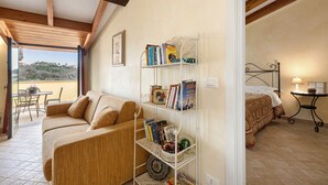Ein gemütliches Zimmer mit einer Couch, einem Metallregal, einem Bett und einem kleinen Tisch mit einer Lampe.