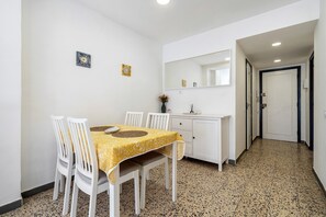 Un coin repas comprenant une table, des chaises, un meuble blanc et un miroir.