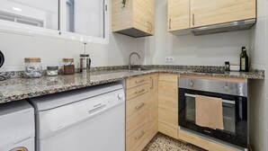 Cocina compacta con lavavajillas, horno y armarios de madera.