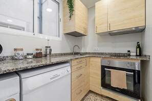 A compact kitchen with a dishwasher, oven, and wooden cabinets.