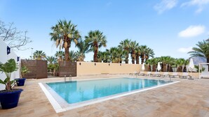 A swimming pool with lounge chairs and palm trees. - Apartment 'Finca Wapa - Studio 2' with Sea View, Wi-Fi and Air Conditioning (Frontera)