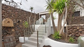A stone wall, a wooden barrel, a staircase with metal railings, and a birdcage. - Apartment 'Finca Wapa - Studio 2' with Sea View, Wi-Fi and Air Conditioning (Frontera)