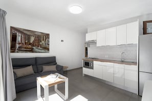 A modern kitchen with white cabinets, a built-in oven, and a stainless steel refrigerator.