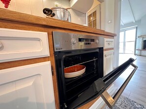 A kitchen with a built-in oven, a wooden countertop, and a window.