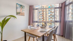 A dining area with a table, chairs, a potted plant, and a painting on the wall. - Apartment 'Aquario' with Sea View, Wi-Fi and Air Conditioning (Benalmádena)