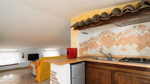 Una cocina compacta con salpicadero de azulejos, estufa integrada y refrigerador.
