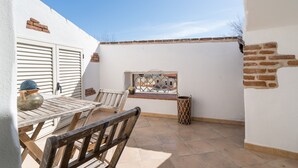 Un patio con una mesa y sillas de madera, una ventana con vistas y un cubo de basura.