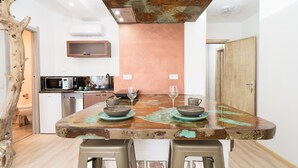 Une cuisine avec une table rustique, des tabourets et un élément décoratif en forme de tronc d’arbre.