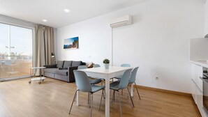 Un salon moderne comprenant une table à manger, des chaises, un canapé et une grande fenêtre.