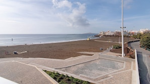 Une plage avec une promenade dallée, un lampadaire et des bâtiments en arrière-plan.