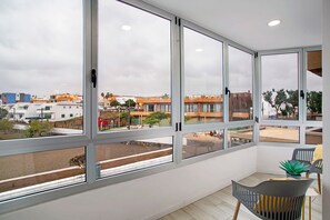 Une pièce avec de grandes fenêtres, une chaise et une petite table.