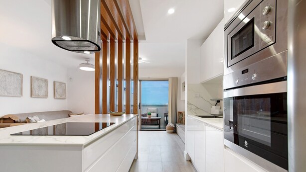 A modern kitchen with a central island, stainless steel appliances, and a view to the outside.