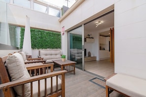 Ein modernes Interieur mit einer Couch, Holztischen, einer grünen Wand und einer Küchenzeile.