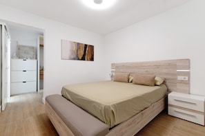 Ein Schlafzimmer mit einem Bett, einem Nachttisch, einer Bank und einem Bild an der Wand.