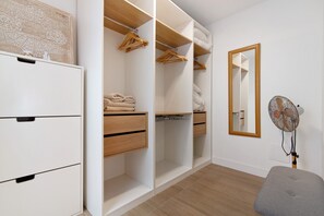 A walk-in closet with wooden drawers, hanging space, and a mirror.