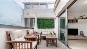 A modern outdoor seating area with wooden furniture and a green wall.