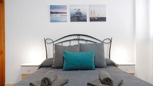 A neatly made bed with a metal headboard, two bedside tables with lamps, and three framed pictures on the wall.