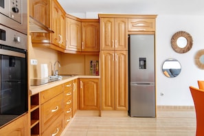 A kitchen with wooden cabinets, a stainless steel refrigerator, and a built-in oven. - Vacation Apartment 'La Calma En Playa De Salinetas' with Wi-Fi (Telde)