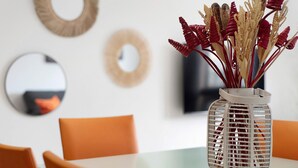 A dining table with chairs, a vase with decorative elements, and wall decor.