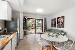 Una cocina moderna con un lavamanos, estufa y comedor con sillas y una mesa.