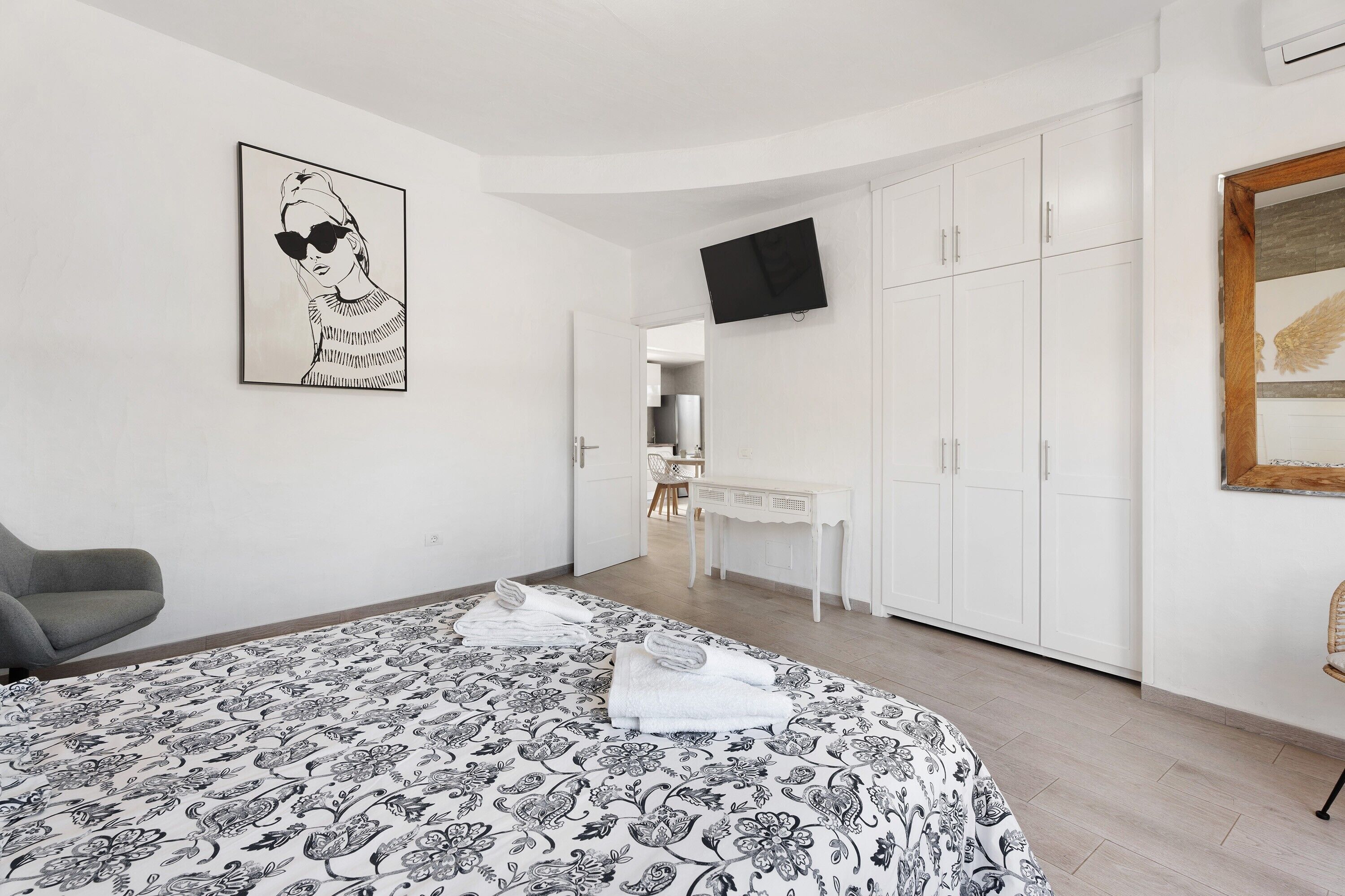 A bedroom with a bed, a desk, a chair, a wardrobe, and a television.