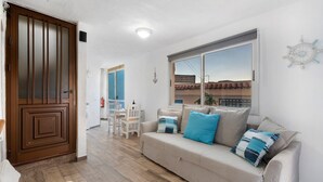 Una sala de estar con sofá, una mesa de comedor y una ventana con vistas.