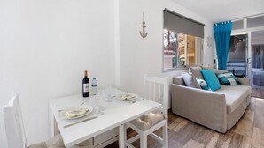 Un comedor con una mesa dispuesta para dos personas, un sofá y una ventana con cortinas.