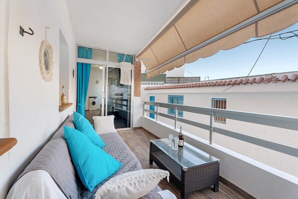 A balcony with a sofa, table, and a view of the building's exterior.