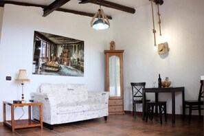 A room with a white sofa, a wooden table with chairs, a mirror, and a hanging light fixture. - Apartment 'Finca Wapa -Rústico' with Sea View, Wi-Fi and Air Conditioning (Frontera)