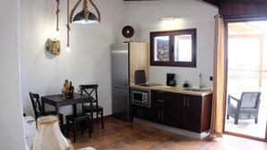 Una cocina compacta con comedor, refrigerador, microondas y ventana sobre el fregadero.