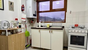 Une cuisine avec des armoires blanches, une cuisinière, une fenêtre et un évier.