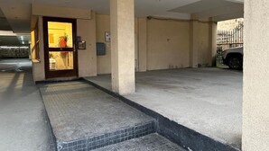 Un espace de stationnement doté d’un sol en béton, d’une entrée carrelée et d’une porte donnant accès à un bâtiment.