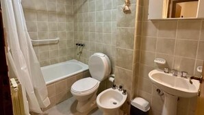 Une salle de bain avec une baignoire, deux toilettes, un bidet et un lavabo.