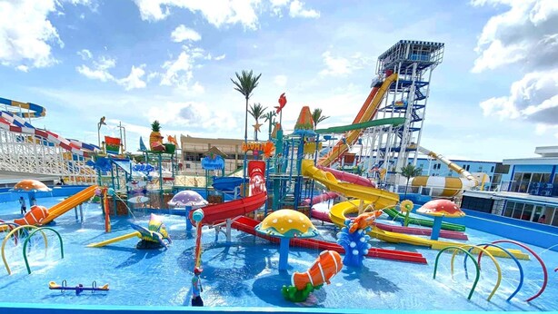 Parque acuático con toboganes, simulador de olas y torre de salvavidas.