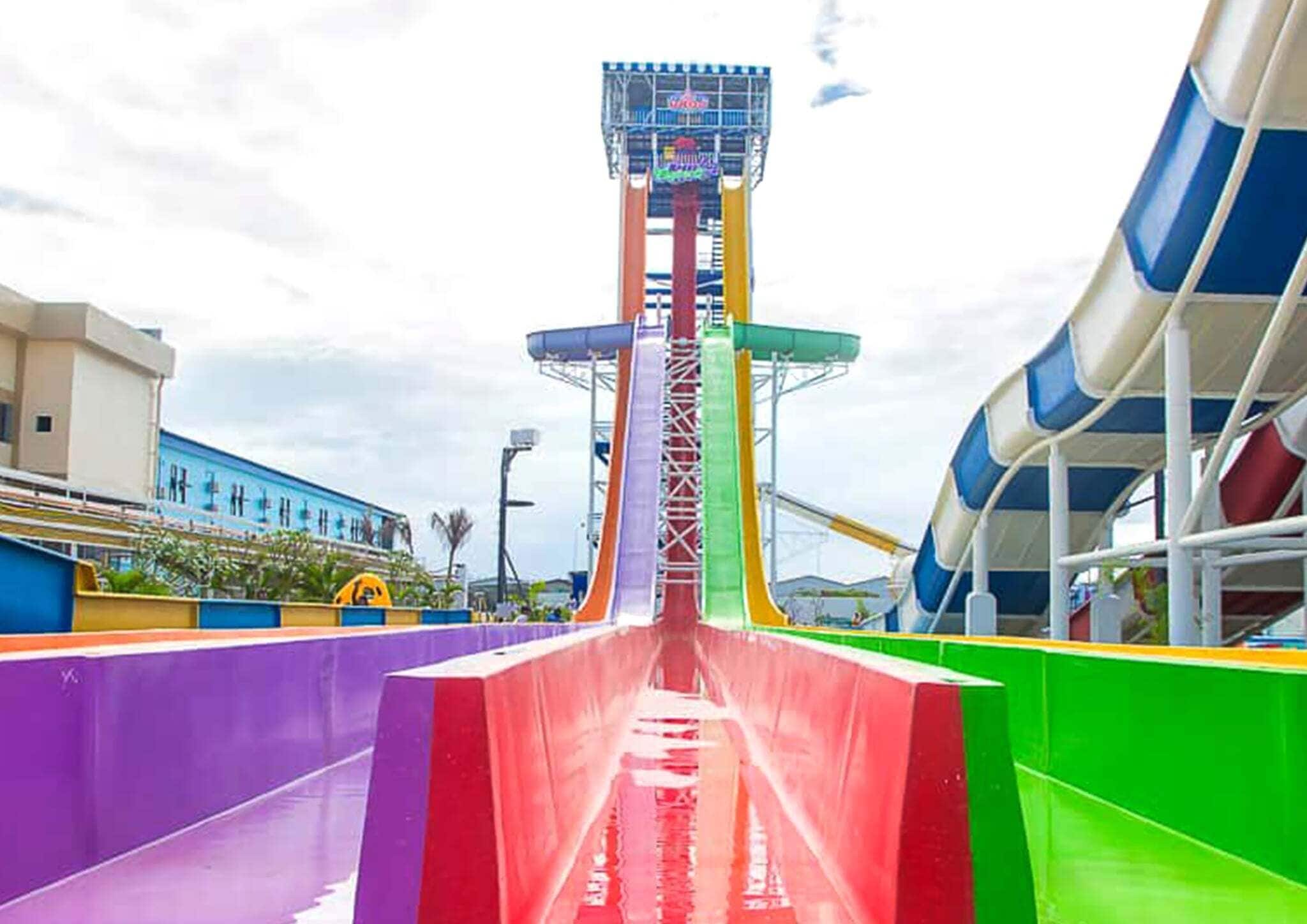 Un tobogán acuático con una torre central, rodeado de barreras de colores.