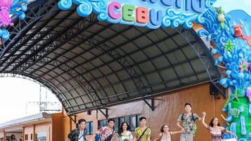 Ein wasserthemen-Eingang mit einem Schild, auf dem 'Waterworld Cebu' steht, und einer Gruppe von Personen in legerer Kleidung.