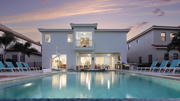 A modern hotel with a swimming pool, lounge chairs, and a two-story building with balconies. - Beautiful Villa with First Class Amenities in Reunion Resort, Orlando Villa 1011 (Orlando)