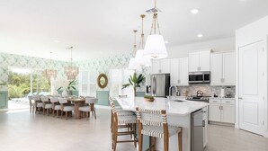 A modern kitchen with white cabinets, stainless steel appliances, and a central island with bar stools. - Beautiful Villa with First Class Amenities in Reunion Resort, Orlando Villa 1011 (Orlando)